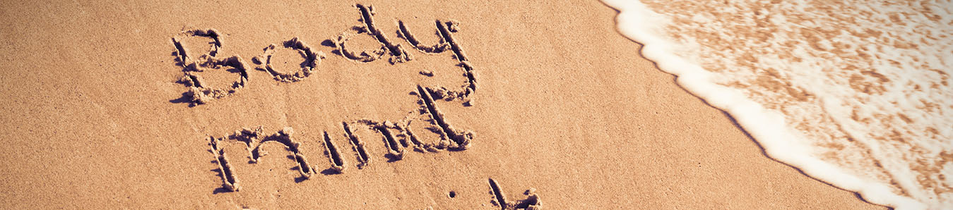 Body mind spirit text written on sand with surf